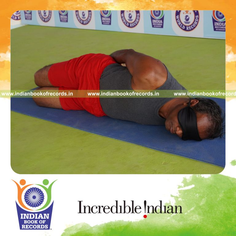 individual holding vama parsva dhanurasana yoga pose blindfolded for record in Indian Book of Records