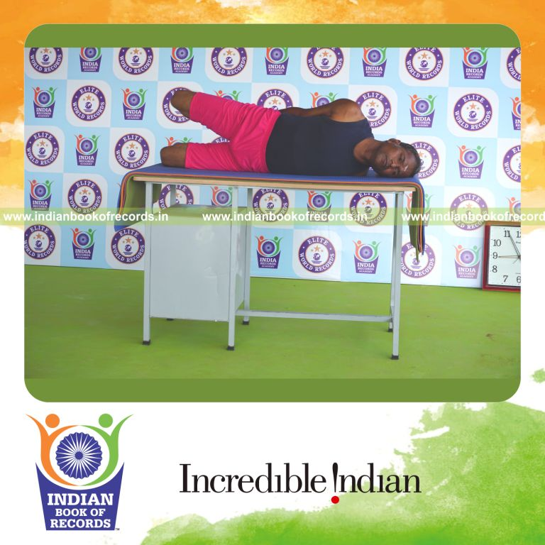 an individual holding vama parsva dhanurasana yoga pose on a table for the longest duration with flexibility and control for a record in Indian Book of Records