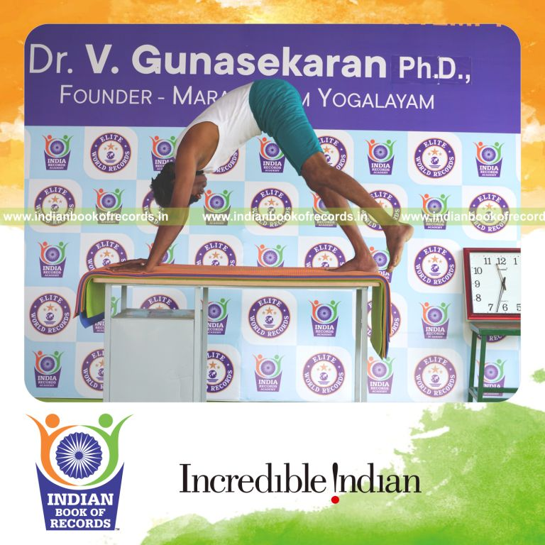 an individual holding vama parsva ekapada adho mukha svanasana yoga pose blindfolded on a table continuously for the longest duration with balance and control for a record in Indian Book of Records
