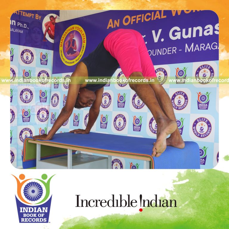 an individual holding vama parsva ekapada adho mukha svanasana yoga pose on a table for the longest duration with control and balance for a record in Indian Book of Records