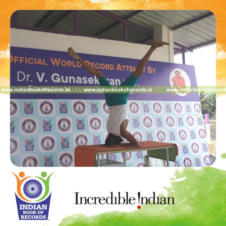 an individual holding vama parsva ekapada salamba sirsasana yoga pose blindfolded on a table continuously for the longest duration with control and balance for a record in Indian Book of Records