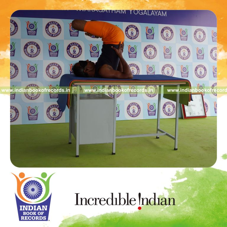 individual holding vama parsva padma sarvangasana yoga pose blindfolded on a table for record in Indian Book of Records
