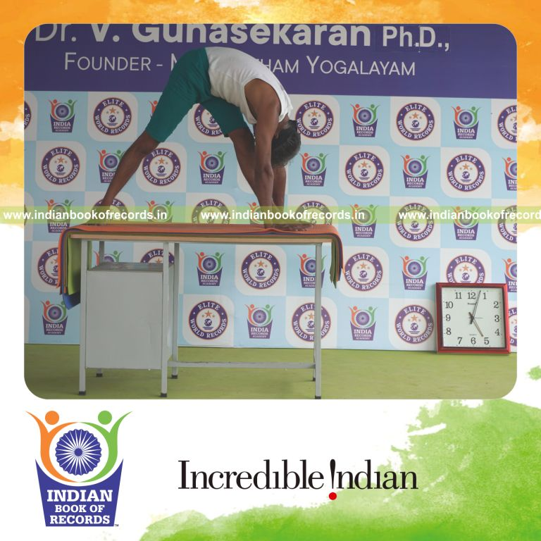 individual holding vama parsvottanasana yoga pose blindfolded on a table for record in Indian Book of Records