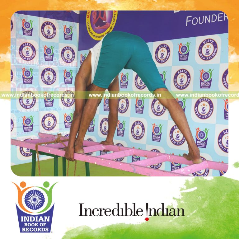 individual holding vama parsvottanasana yoga pose on a ladder for record in Indian Book of Records