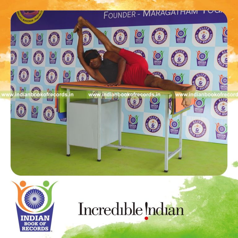 individual holding vama purna anandasana yoga pose blindfolded on a table for record in Indian Book of Records
