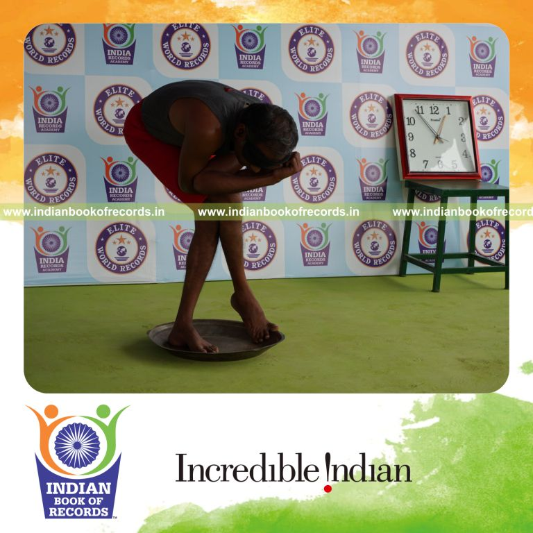 individual holding vama purna garudasana yoga pose blindfolded on a brass plate for record in Indian Book of Records