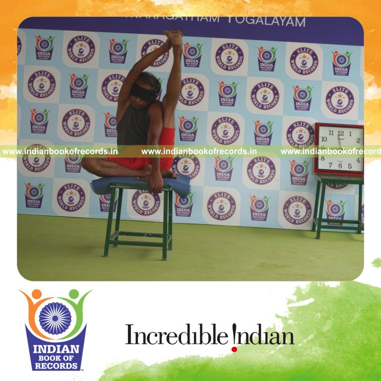 individual holding vama purna krounchasana yoga pose blindfolded on a stool for record in Indian Book of Records