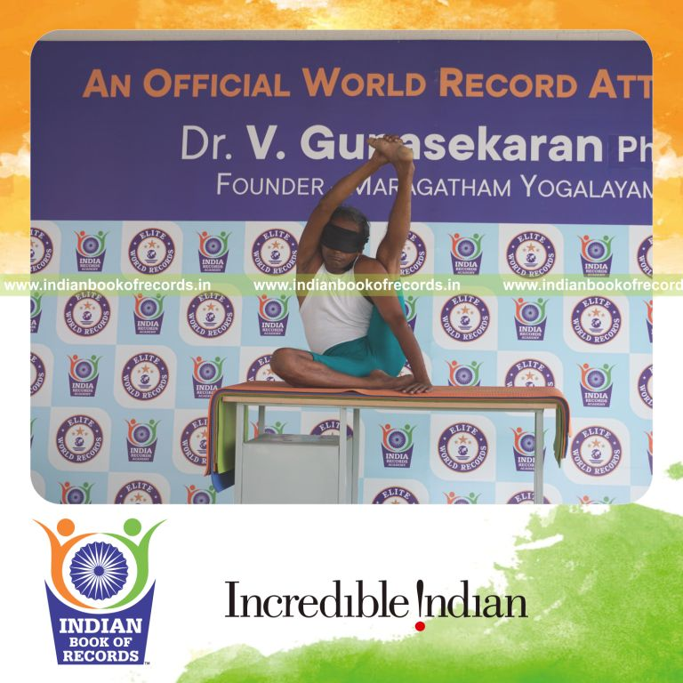 an individual holding vama purna krounchasana yoga pose blindfolded on a table continuously for the longest duration with control and balance for a record in Indian Book of Records