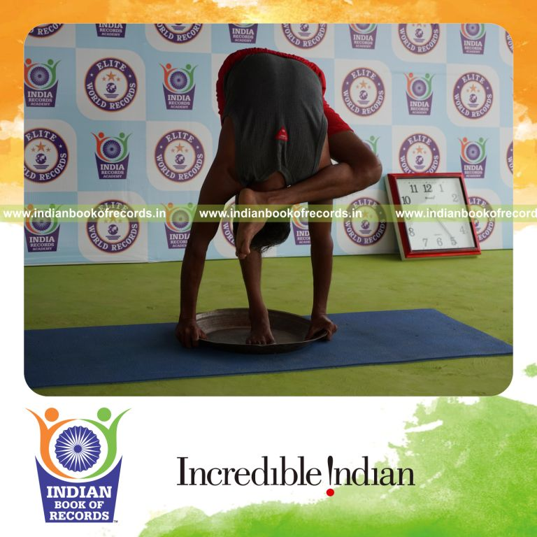 individual holding vama ruchikasana yoga pose blindfolded on a brass plate for record in Indian Book of Records