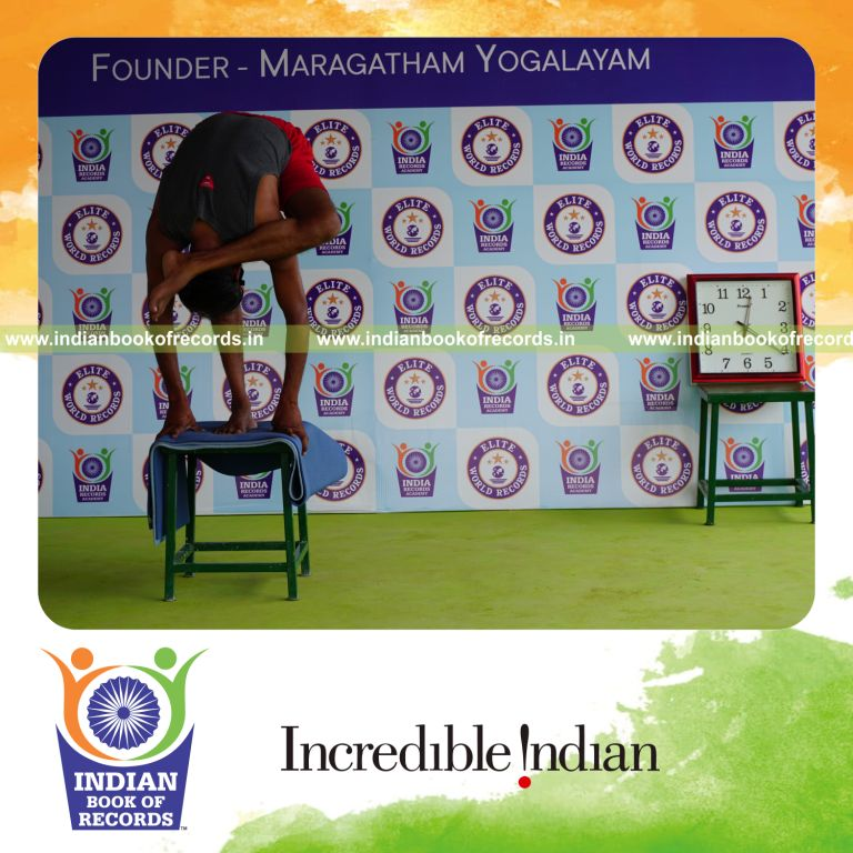 individual holding vama ruchikasana yoga pose blindfolded on a stool for record in Indian Book of Records