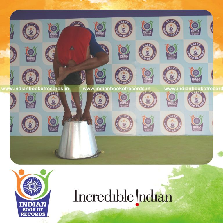 individual holding vama ruchikasana yoga pose on a bucket for record in Indian Book of Records