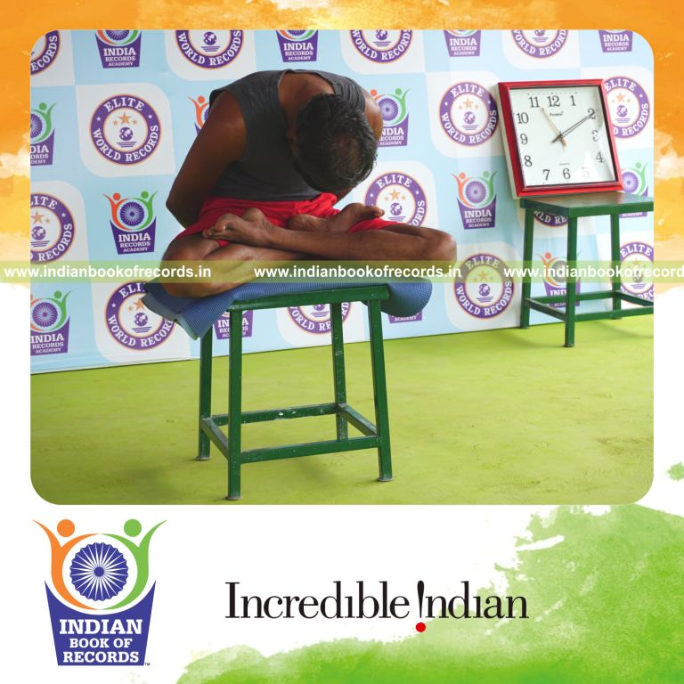 individual holding yoga mudra yoga pose blindfolded on a stool for record in Indian Book of Records