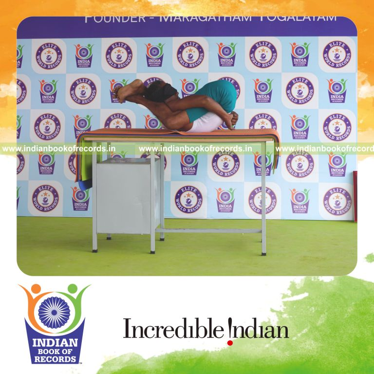 an individual holding yoganidrasana yoga pose blindfolded on a table continuously for the longest duration with control and balance for a record in Indian Book of Records