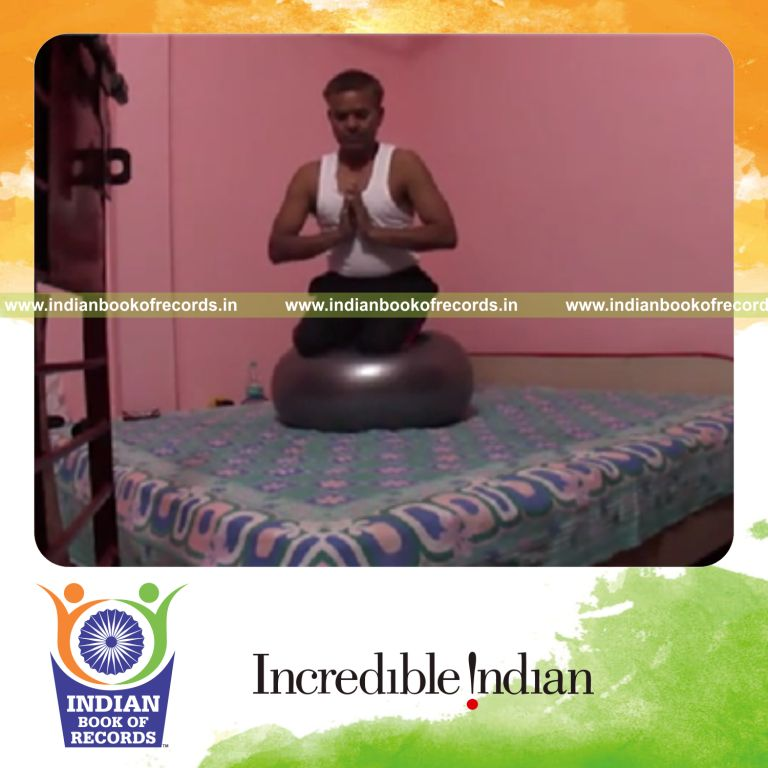 individual sitting on exercise ball holding praying thunderbolt pose for record in Indian Book of Records
