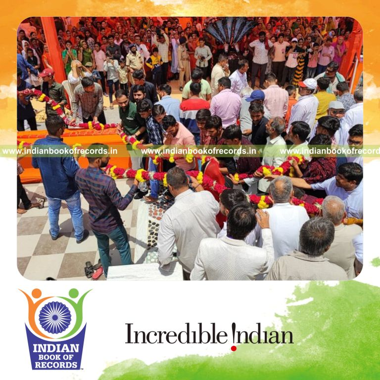 Team presenting an exceptionally long flower garland arranged and measured for a record recognized by Indian Book of Records