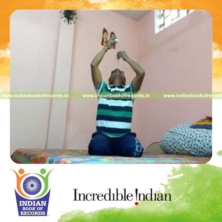individual balancing golf ball on knitting needle on chin while kneeling for record in Indian Book of Records