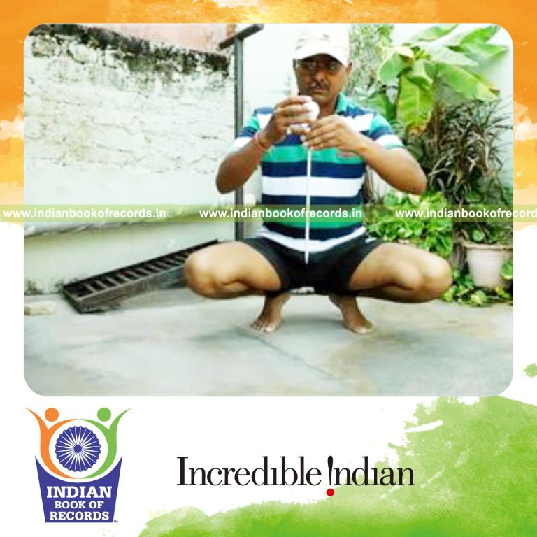 individual balancing golf ball on knitting needle on pinky finger while sitting on toes for record in Indian Book of Records