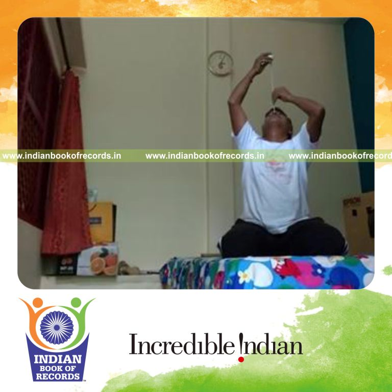 individual balancing golf ball on knitting needle on nose while kneeling for record in Indian Book of Records