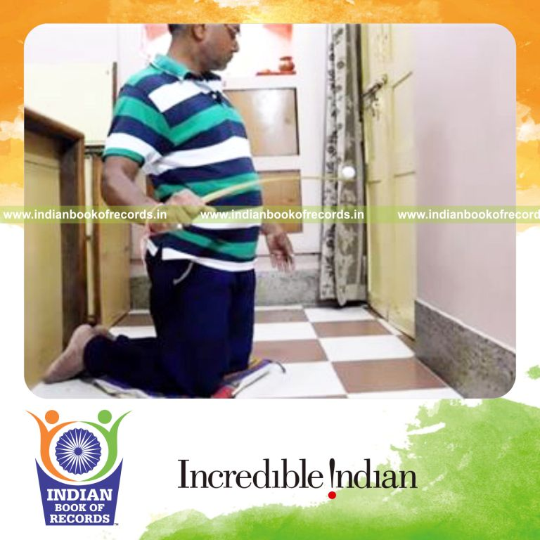 individual balancing golf ball on yardstick while on knees for record in Indian Book of Records