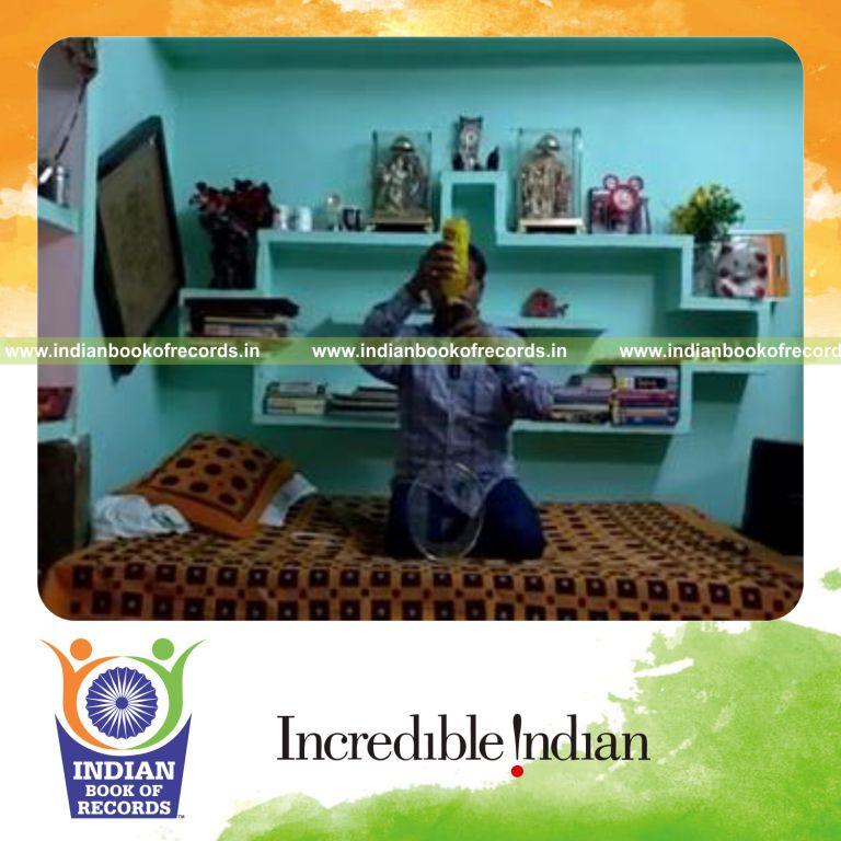individual balancing juice bottle on racquet handle on chin while kneeling for record in Indian Book of Records