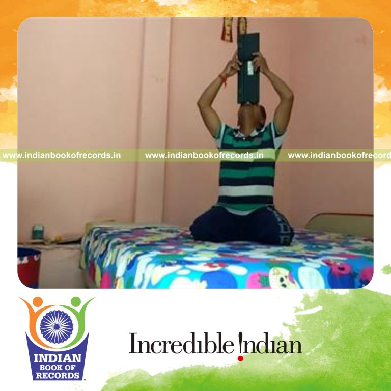 individual balancing computer keyboard on nose while kneeling for record in Indian Book of Records