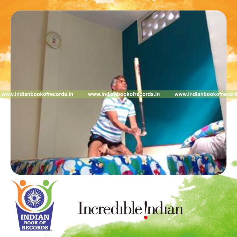 individual performing knee stand holding lotus pose while balancing bat for record in Indian Book of Records