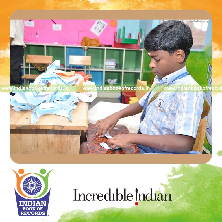 young male creating long origami chain for record in Indian Book of Records
