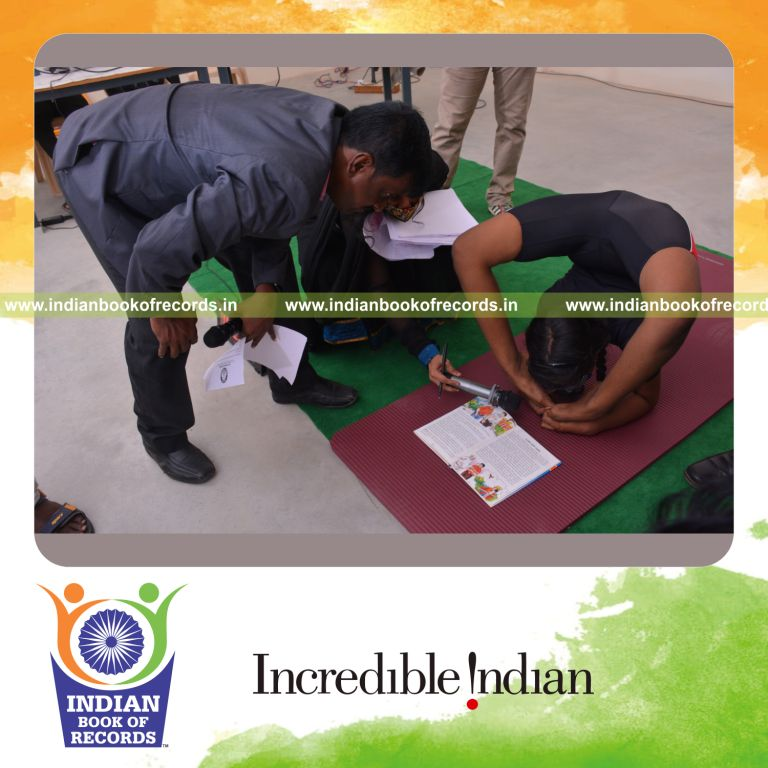 individual female reading book upside down while blindfolded holding viruchikaasana yoga pose for Indian Book of Records