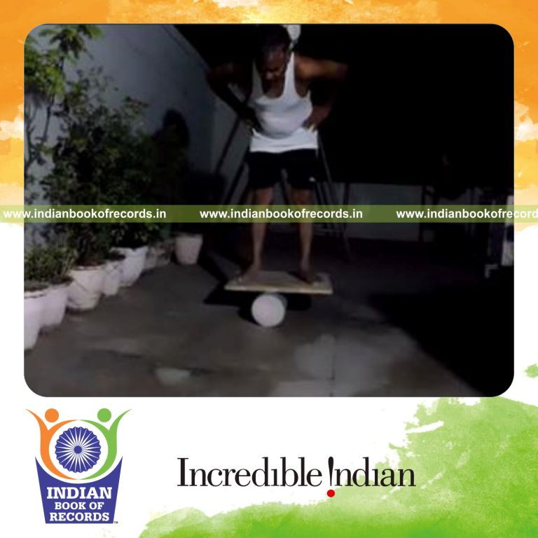 individual holding soccer ball in neck trap while balancing on rola bola for record in Indian Book of Records