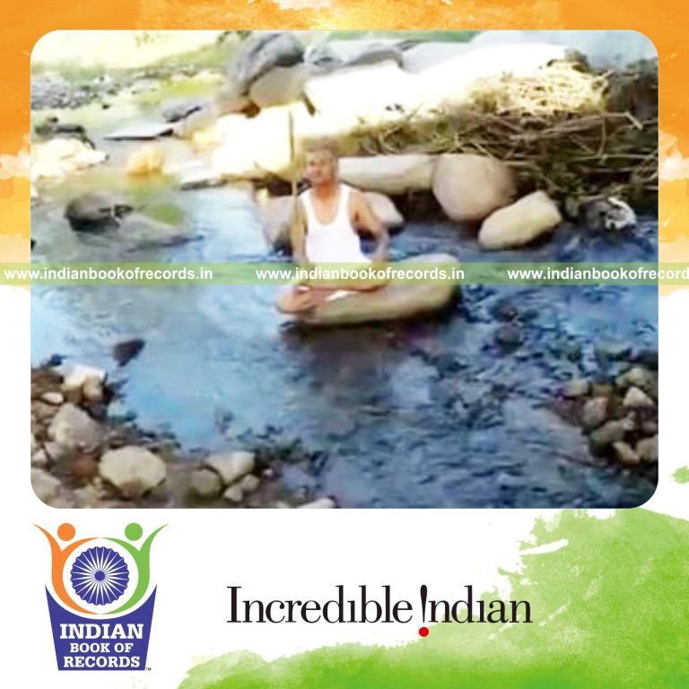 individual balancing stick on finger in lotus pose on rock in creek for record in Indian Book of Records