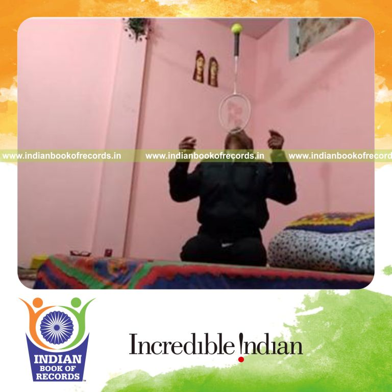 individual balancing tennis ball on badminton racquet handle on chin while sitting for record in Indian Book of Records