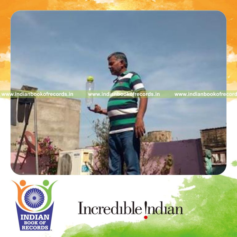 individual balancing tennis ball on water bottle on one finger for record in Indian Book of Records