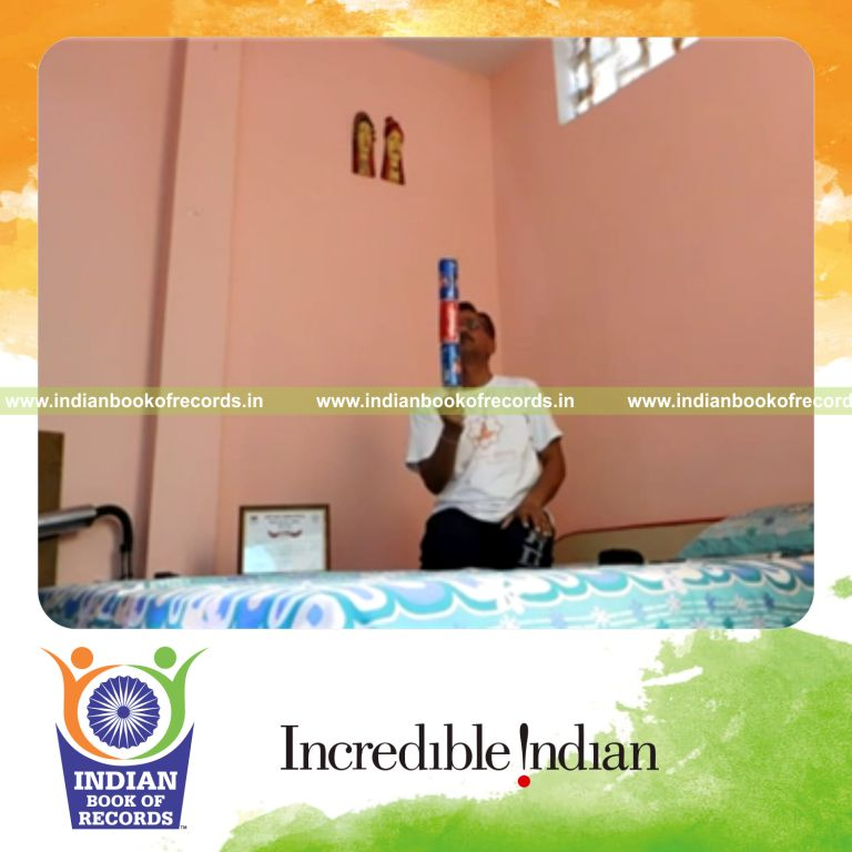 individual balancing three soda cans on thumb while sitting for record in Indian Book of Records