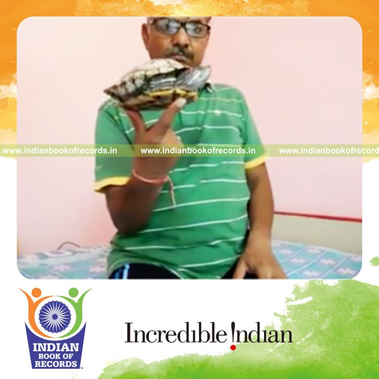 individual balancing turtle on two fingers for record in Indian Book of Records
