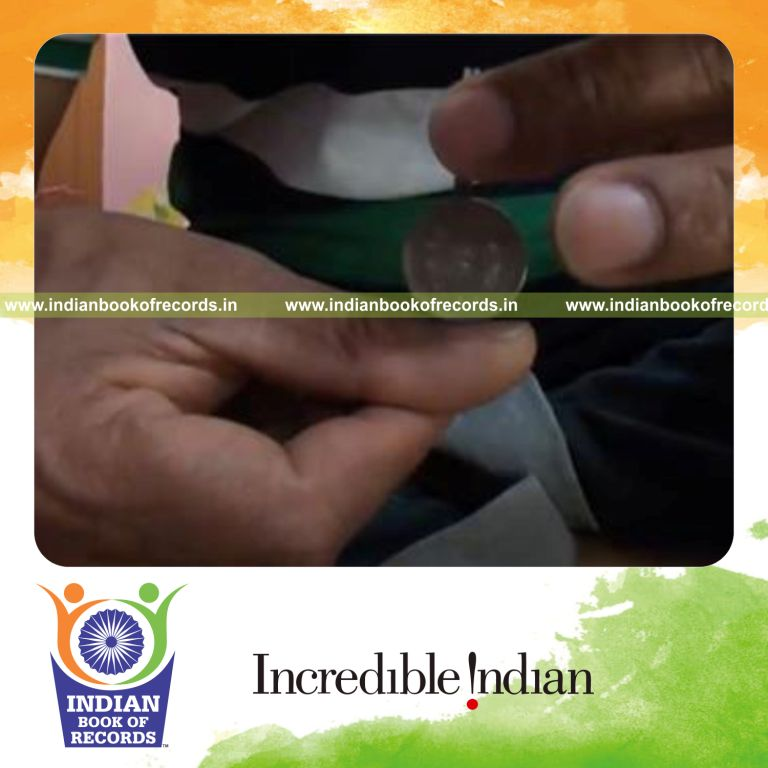 individual balancing two coins crosswise on thumb for record in Indian Book of Records