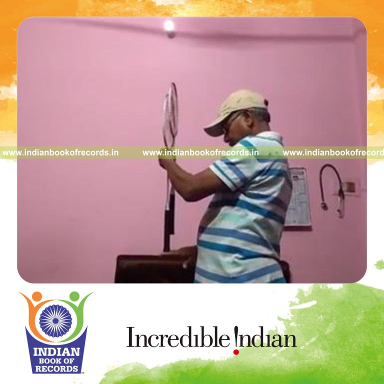 individual balancing two badminton racquets on back of right hand for record in Indian Book of Records