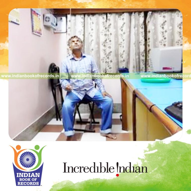 individual balancing wooden dowel on pinky finger while sitting for record in Indian Book of Records