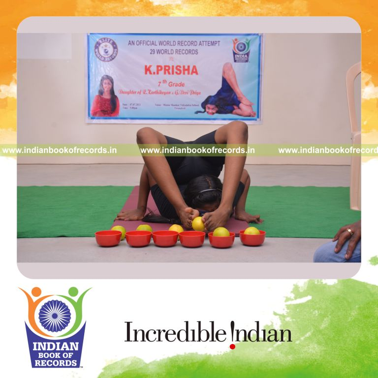 individual female placing oranges in bowl using legs while holding viparita salabhasana blindfolded for Indian Book of Records