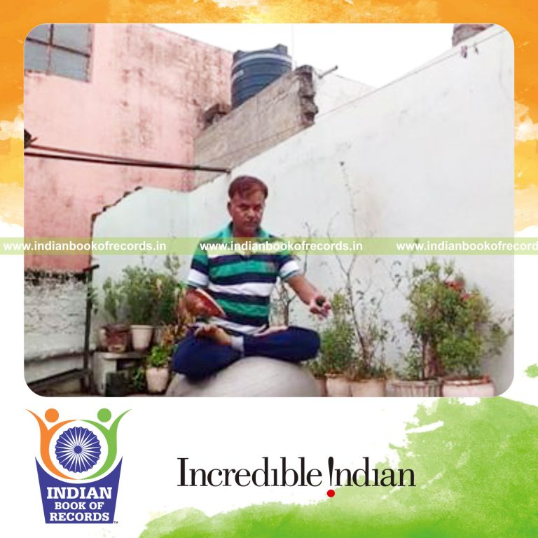individual bouncing squash ball on paddle while holding lotus pose on exercise ball for record in Indian Book of Records