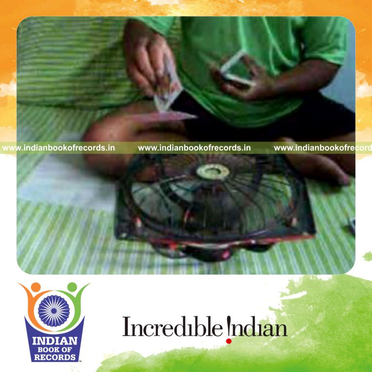individual performing maximum charlier cuts while spinning card with fan for record in Indian Book of Records