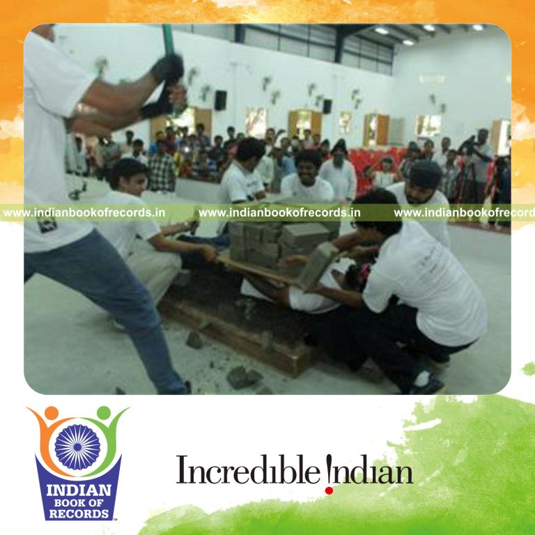 individual breaking concrete blocks on body while lying on bed of nails for record in Indian Book of Records