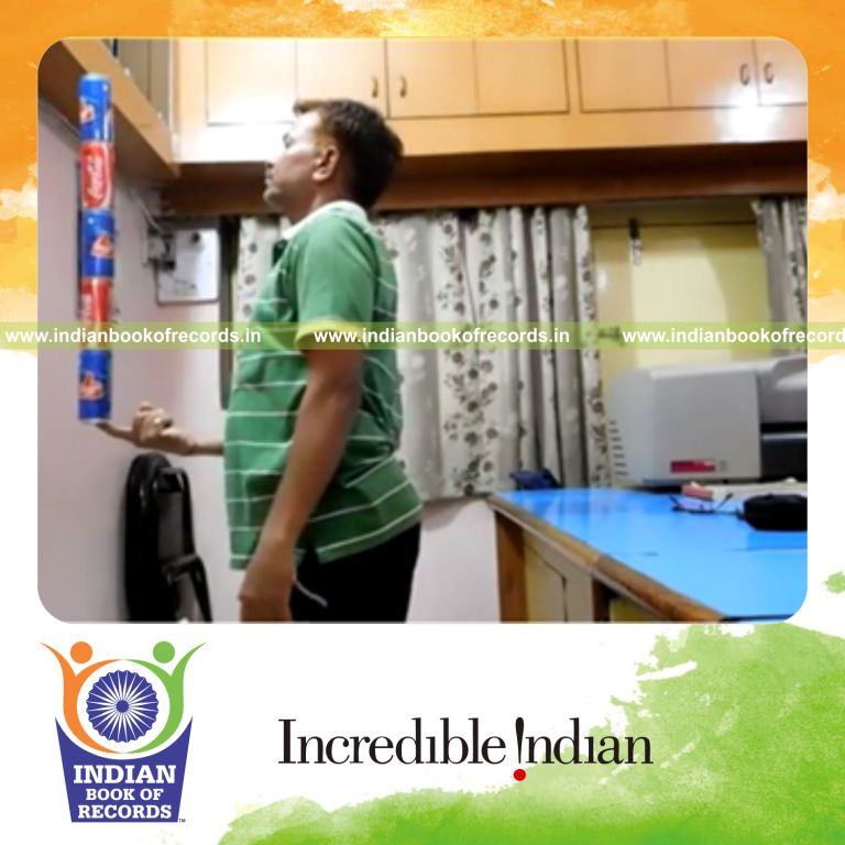 individual performing 360 degree rotations while balancing five cans on right index fingertip for record in Indian Book of Records
