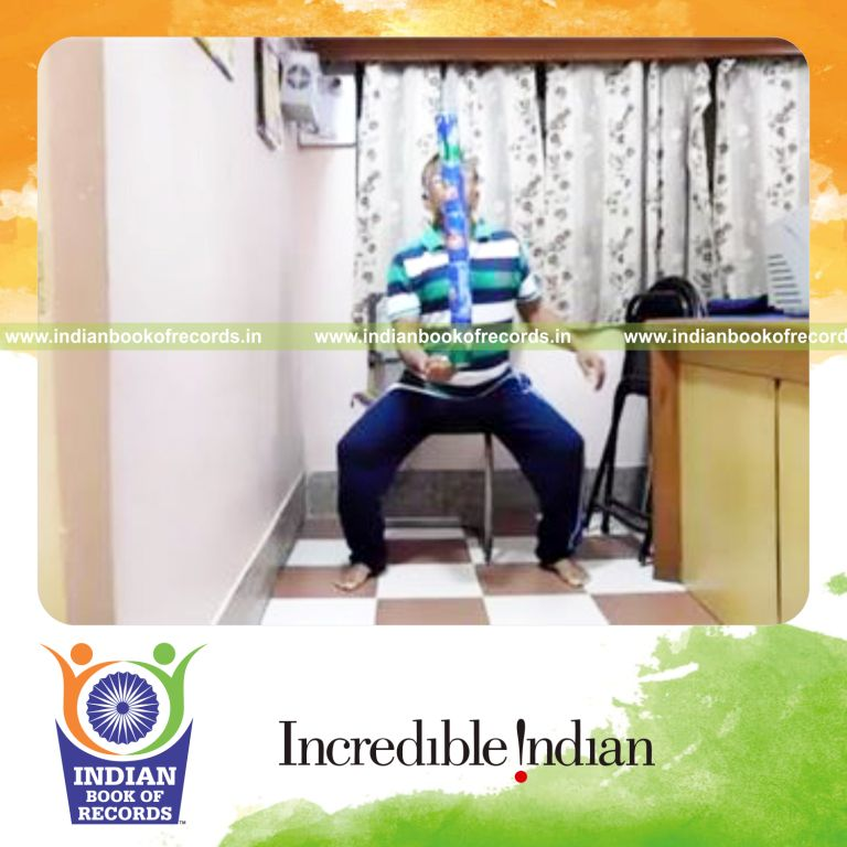 individual standing and sitting repeatedly while balancing five cans on pinky finger for record in Indian Book of Records