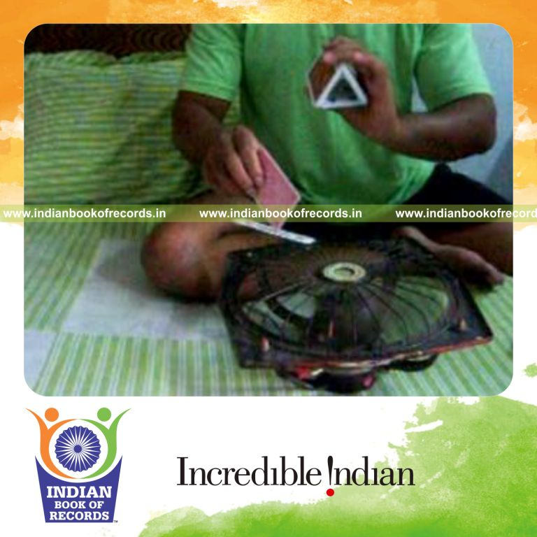 individual performing maximum triangle cuts while spinning card with fan for record in Indian Book of Records