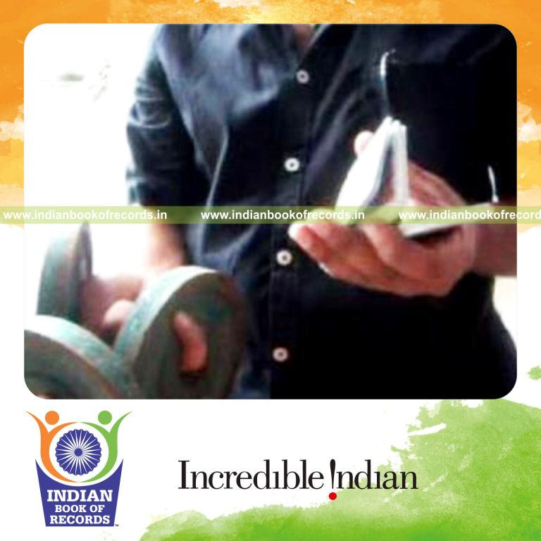 individual performing triple charlier card cuts while holding weight plates for record in Indian Book of Records