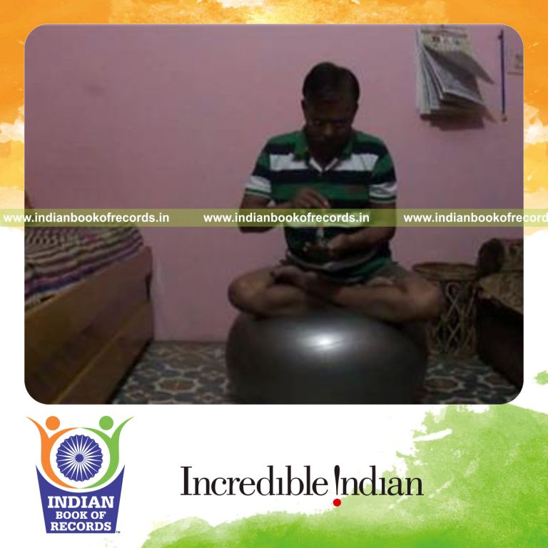 individual stacking dice tower on smartphone while holding lotus pose on exercise ball for record in Indian Book of Records